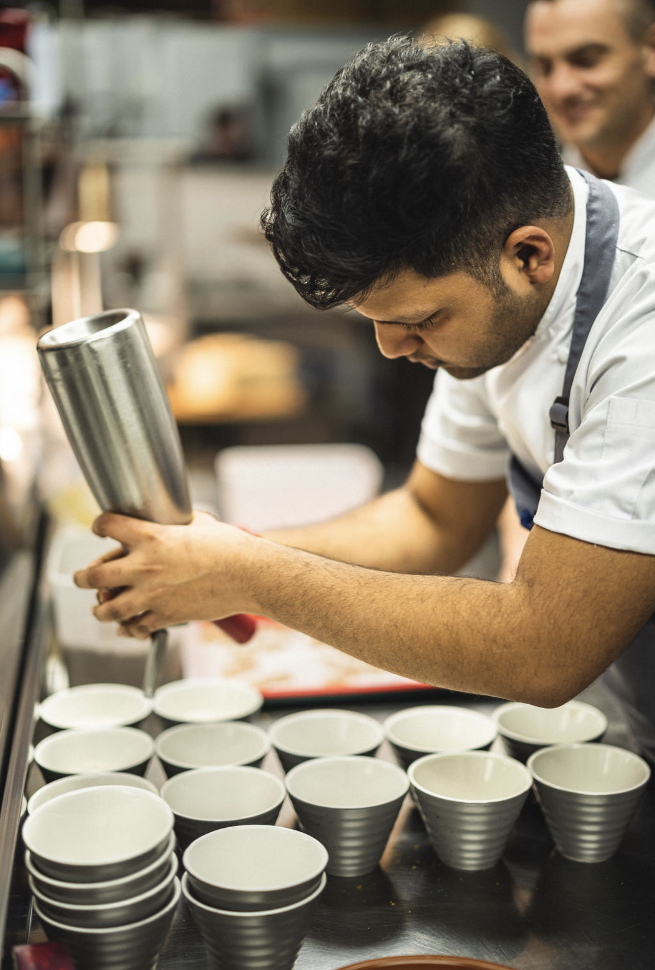 Male chef piping ingredients into a small dish